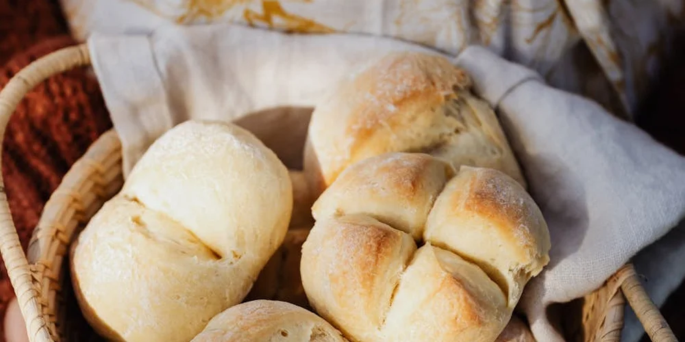 Soft bread rolls in a woven basket lined with a cloth.