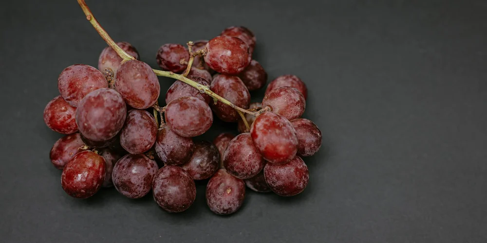A bunch of red grapes on a dark slate surface