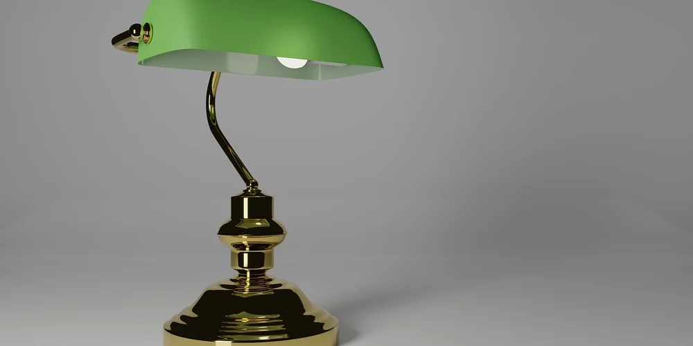 Green desk lamp with brass base on a neutral gray background