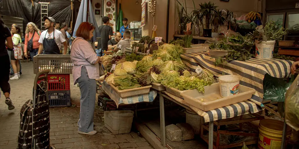 Market scene with fresh leafy greens and vegetables at a vendor table.