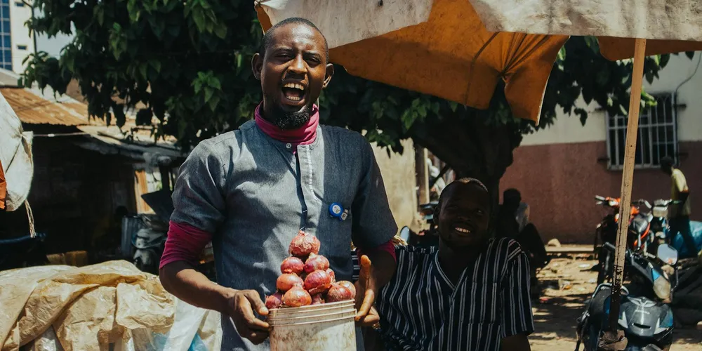 Outdoor market vendor holding a basket of red fruits, illustrating diverse food options for terrestrial turtles.