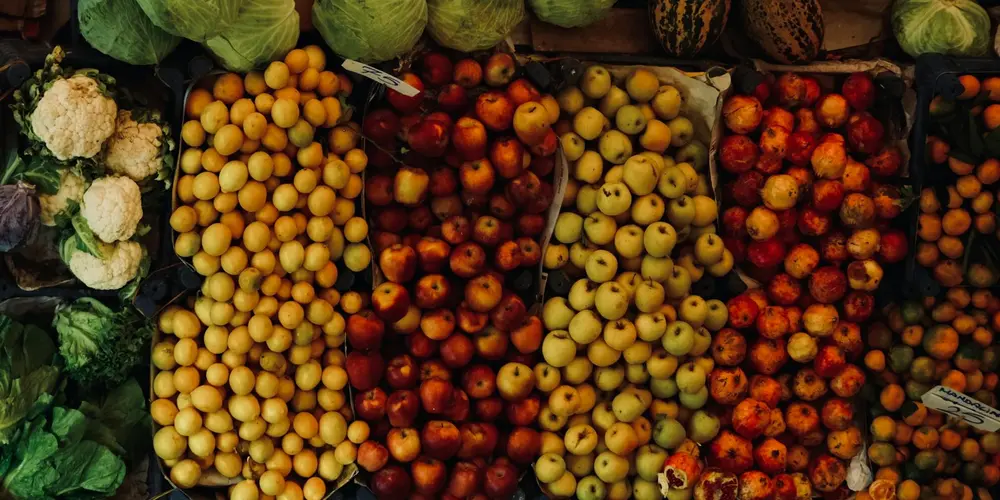 A row of market-style bins filled with assorted fresh fruits and vegetables, illustrating the variety of ingredients that could be used in a homemade turtle diet.