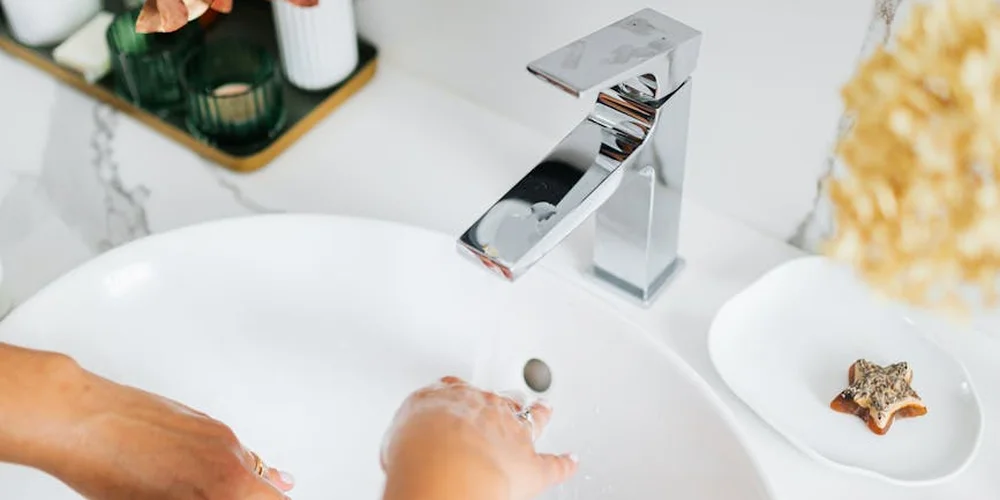 Hands washing under a modern faucet at a sink, emphasizing hygiene to prevent the spread of turtle-associated Salmonella.