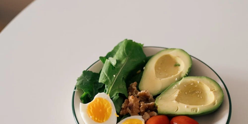Plate with avocado halves, leafy greens, and a boiled egg, illustrating a balanced, protein-containing meal for turtles.