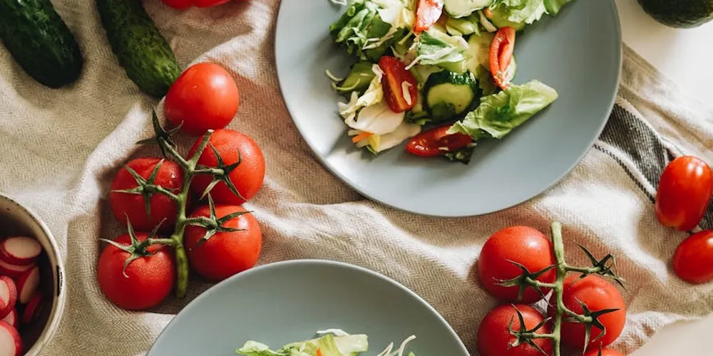 Fresh salad on a plate featuring leafy greens, cucumber slices, and cherry tomatoes.