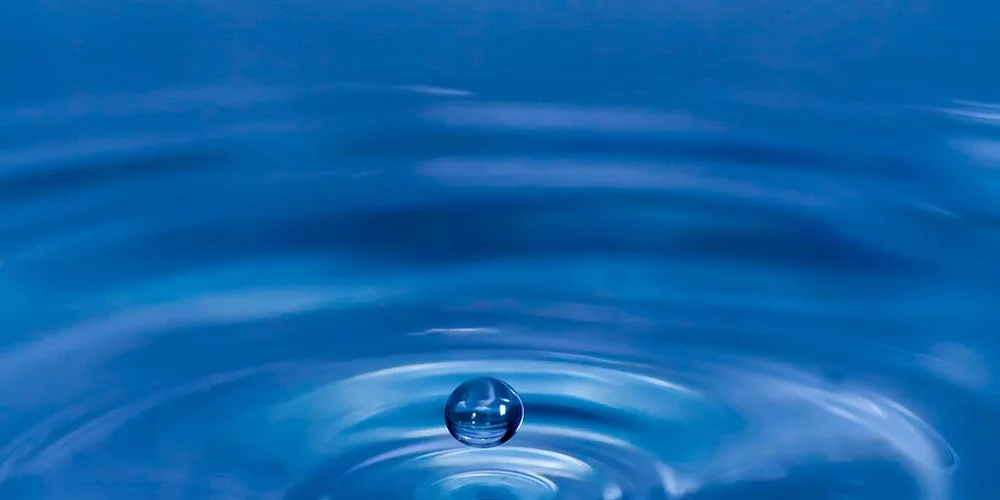Close-up of a water droplet creating ripples on the surface of aquarium water