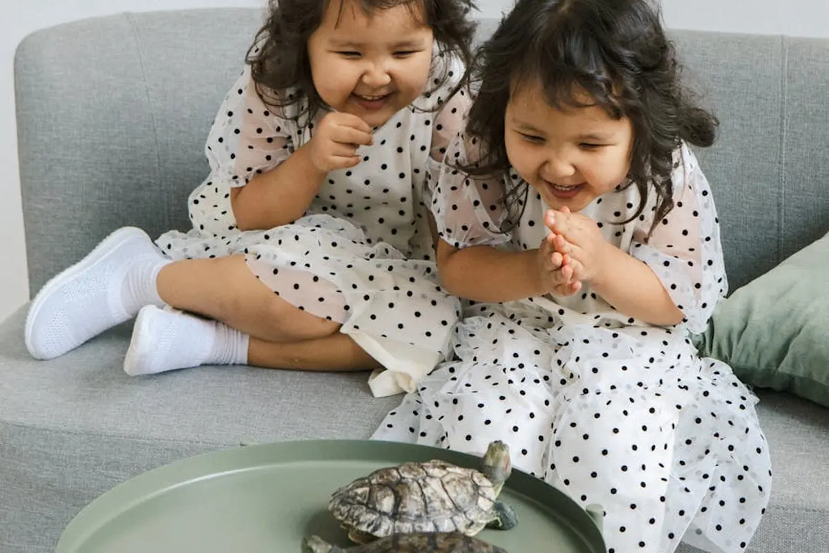 Smiling woman with a towel wrapped around her head, applying foamy face wash in a bathroom.