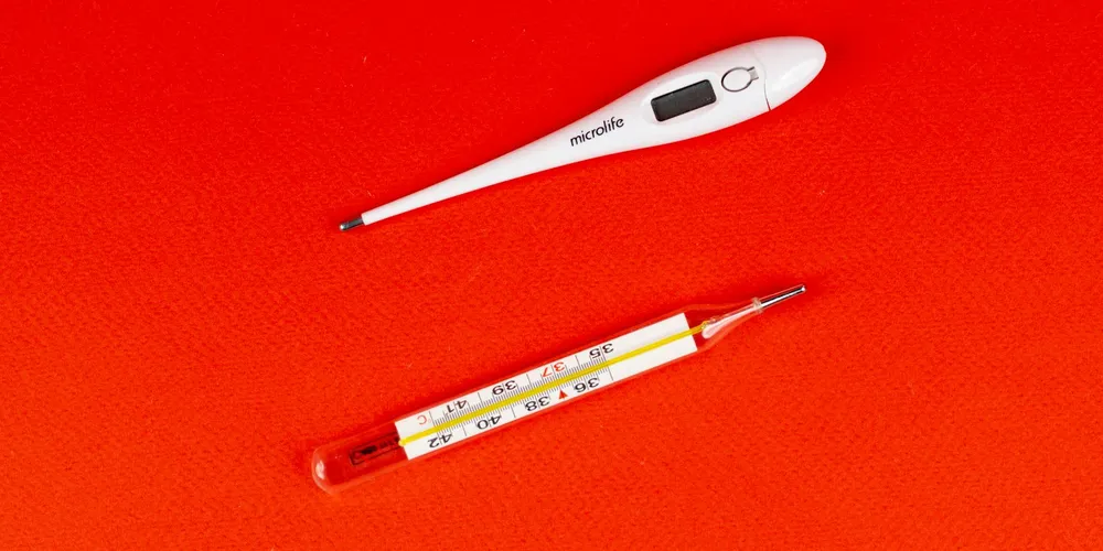 Two thermometers on a bright orange-red background.