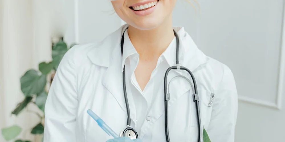 Portrait of a veterinarian in a white coat with a stethoscope, smiling in a clinical setting.