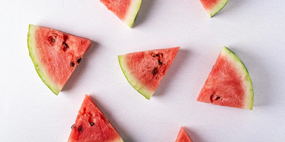 Watermelon wedges on a white surface, illustrating a hydrating, moderate treat for turtles as part of a balanced diet.